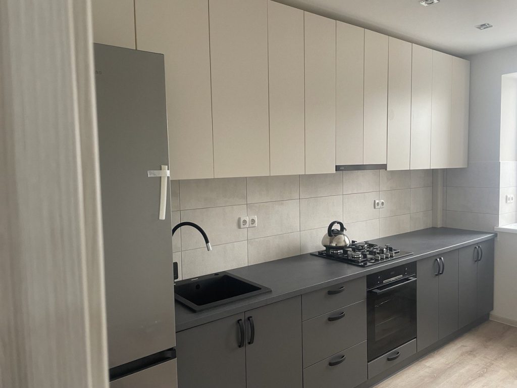 kuchnia w nowym mieszkaniu z jasną zabudową i ciemnym blatem