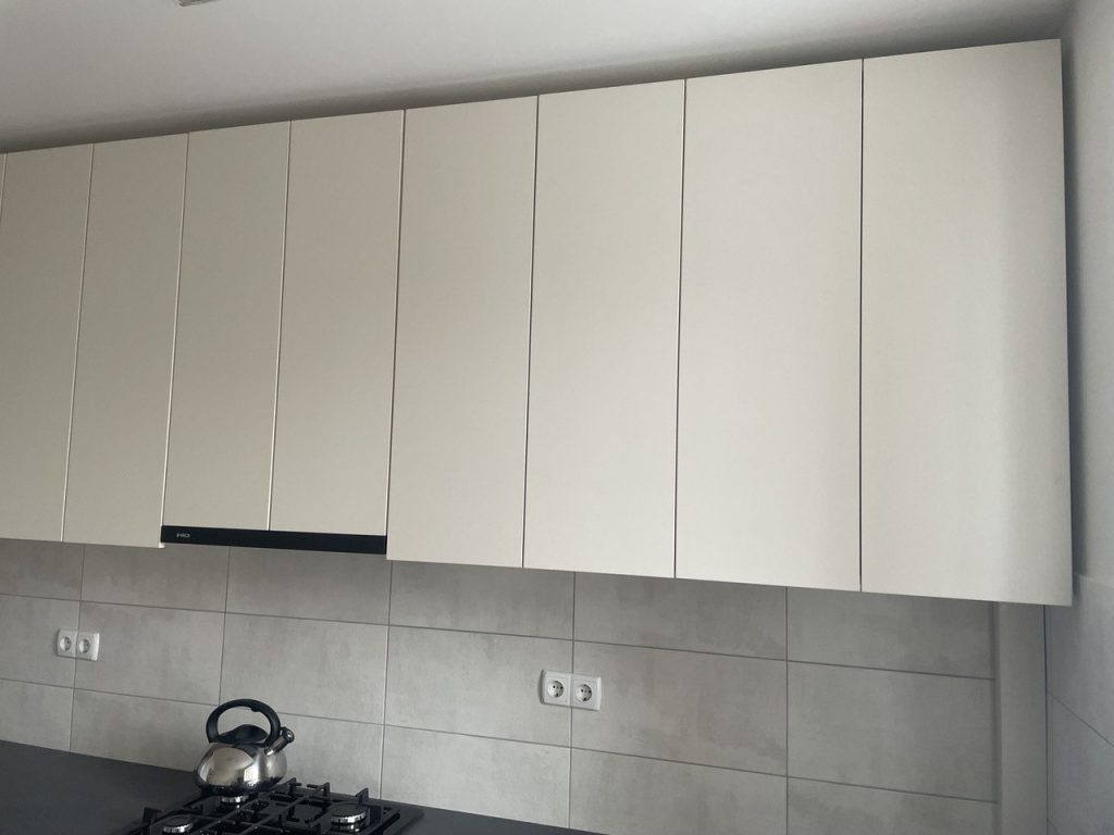 prosta kuchnia w mieszkaniu z jasnymi frontami i szarym blatem