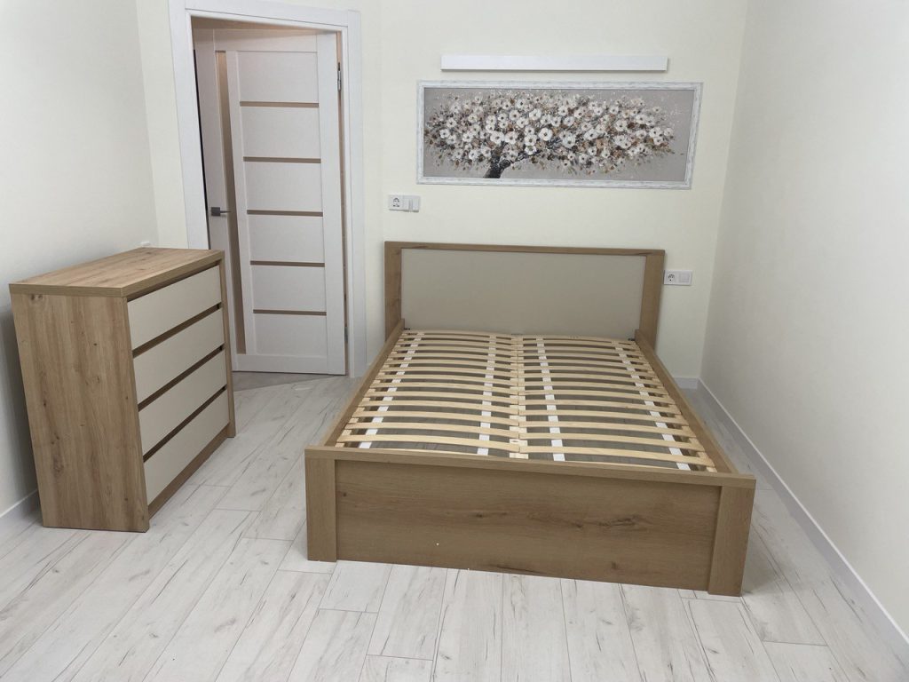 sypialnia w mieszkaniu z drewnianym łóżkiem i komodą