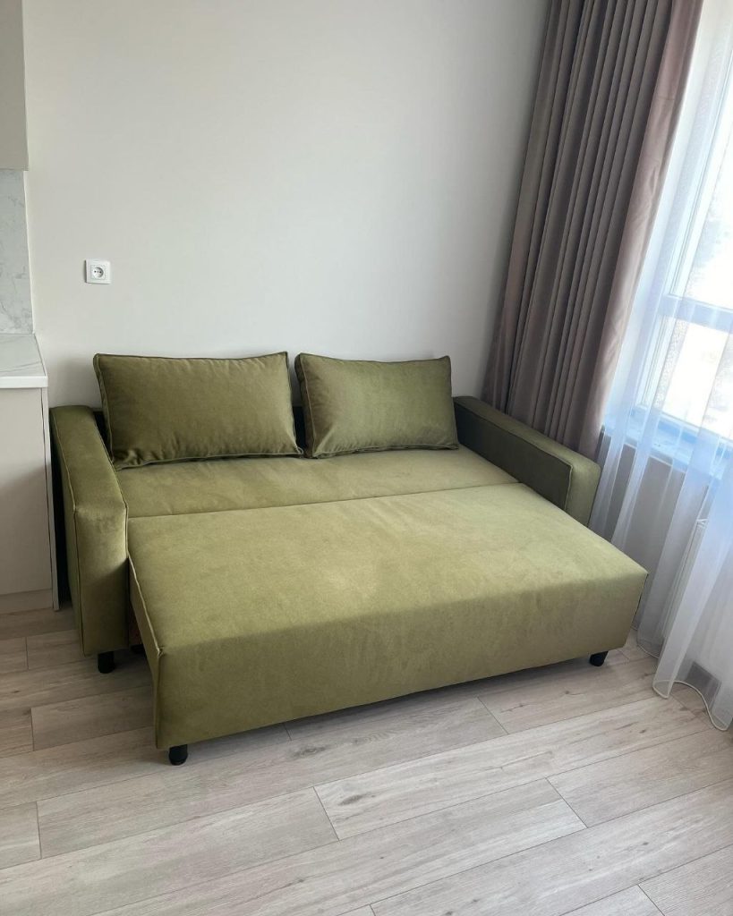 kompaktowa zielona sofa z pojemnikiem na pościel do małego mieszkania