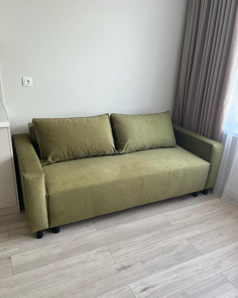 zielona sofa rozkładana z funkcją spania w mieszkaniu pod wynajem